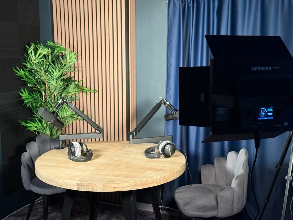 The podcast studio in Gibraltar, with two Shure SM7dB microphones on boom arms over a round oak table